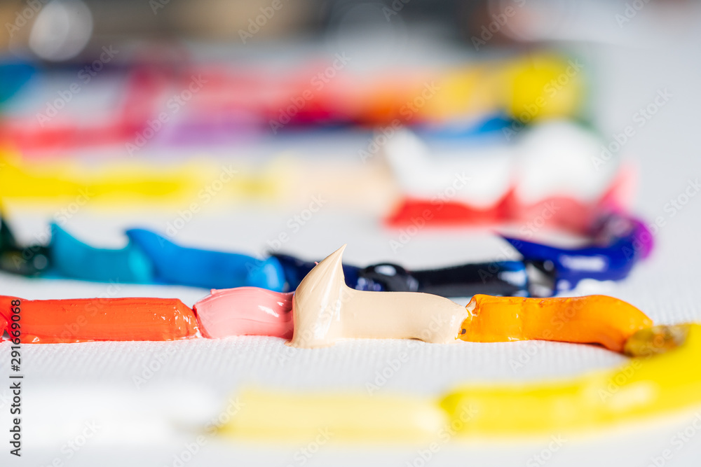 Different bright colors of oil paints are mixed on a palette close-up. Different bright colors of oil paints are mixed on a palette close-up.