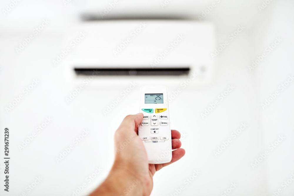 Modern air conditioner unit with a hand holding a remote. Modern air conditioner unit with a hand holding a remote.