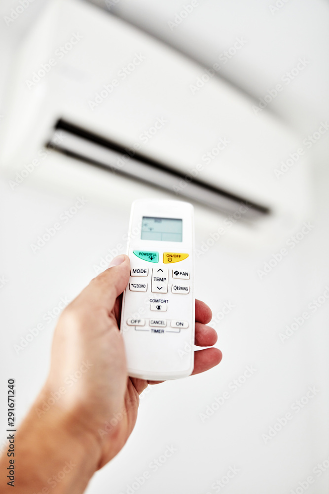 Modern air conditioner unit with a hand holding a remote. Modern air conditioner unit with a hand holding a remote.