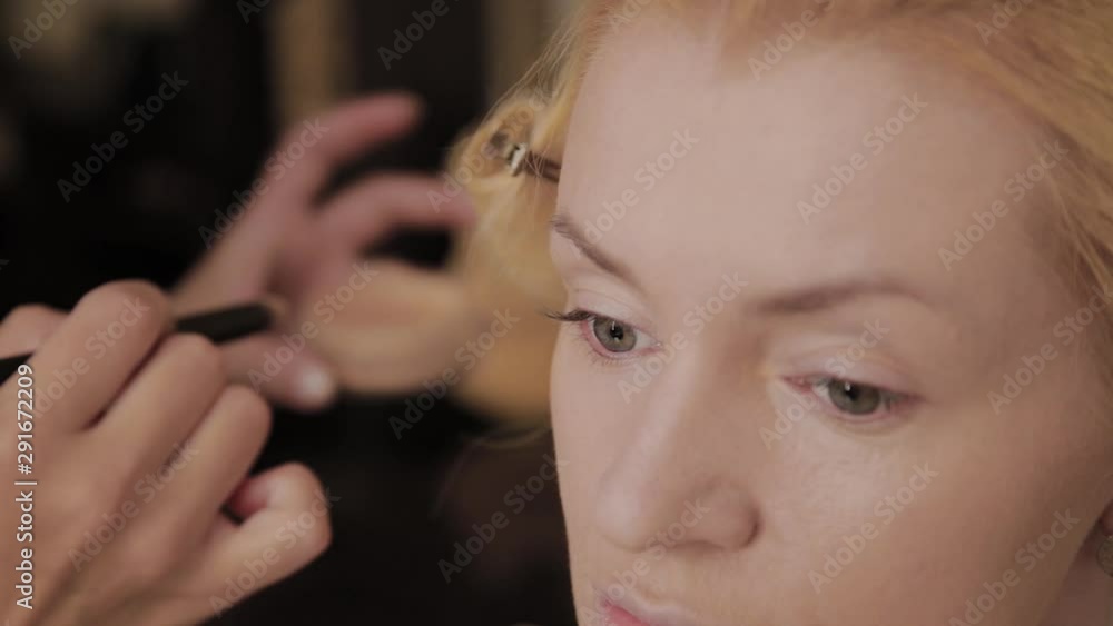 Professional make-up artist applies make-up photo of model to woman. Professional make-up artist applies make-up photo of model to woman.