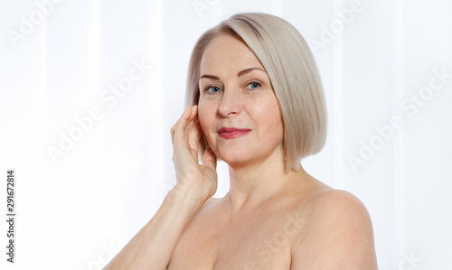 Portrait of cheerful senior woman smiling while looking away at spa. Happy mature woman after spa massage and anti-aging treatment on face. Realistic images with their own imperfections. photo