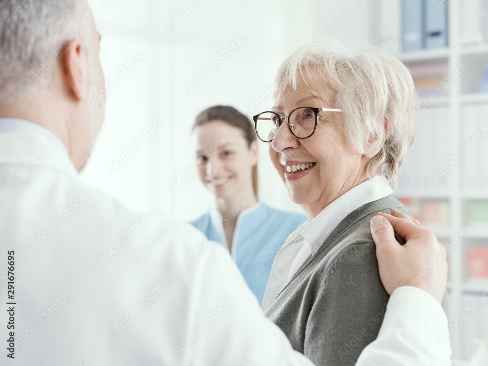Fototapeta premium Smiling senior lady meeting a doctor at the clinic