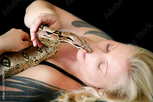 Portrait of girl with Boa constrictor snake. Beautiful woman holds snake in hands and posing in front of camera. Exotic tropical cold blooded reptile, non poisonous Boa constrictor species of snake.