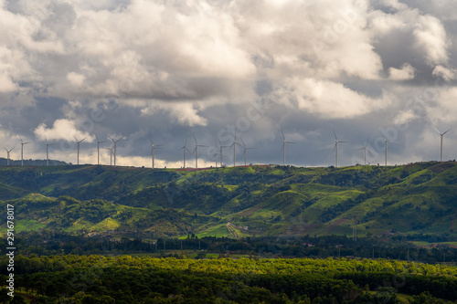 Wind turbines on top mountain with cloudy background.