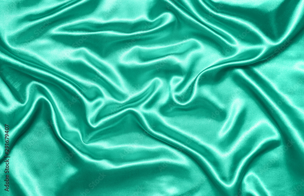 Close up of ripples on silk fabric. Satin textile background. Green color. Top view. Color of the year 2020 Close up of ripples on silk fabric. Satin textile background. Green color. Top view. Color of the year 2020