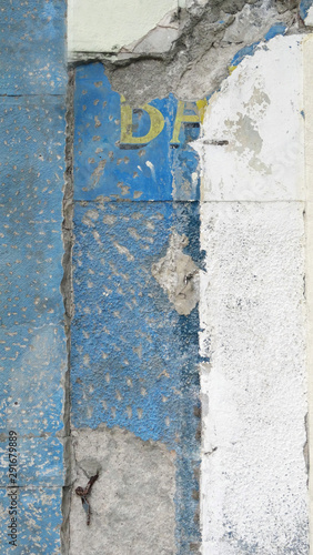 : surface of old blue and white exterior wall with yellow letters. Picked coat before restoration work