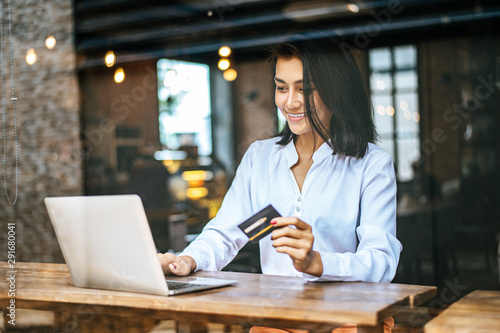 Foto woman sat with a laptop and paid with a credit card in a coffee shop