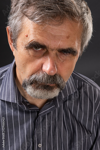 Elderly angry gray-haired man looking sullenly photo