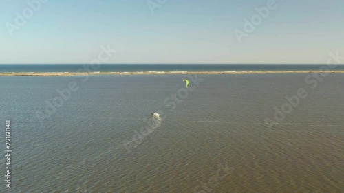 Aerial view of kitesurfer gliding and jumping across ocean