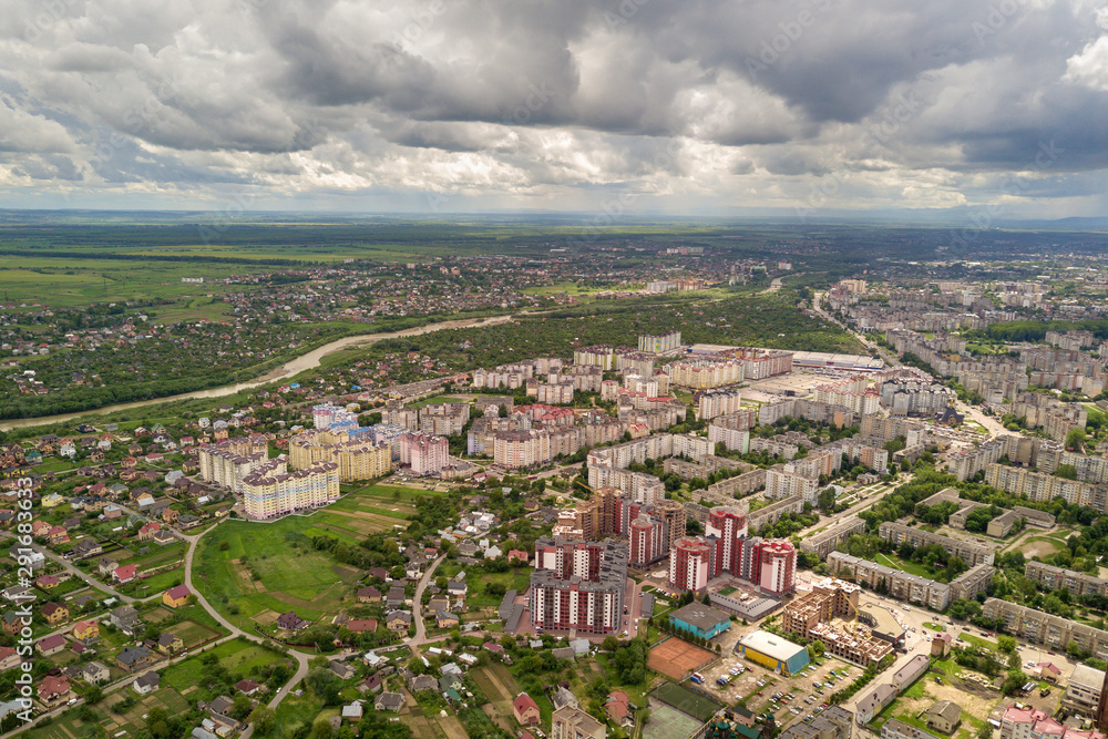 Aerial view of town or city with rows of buildings and curvy streets in summer. Urban landscape from above.