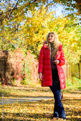 Girl enjoy autumn walk. Clothing for autumn walk. Woman wear coat or warm jacket while stand in park yellow foliage background. Must have fall wardrobe. Be bright this autumn. Autumn season fashion