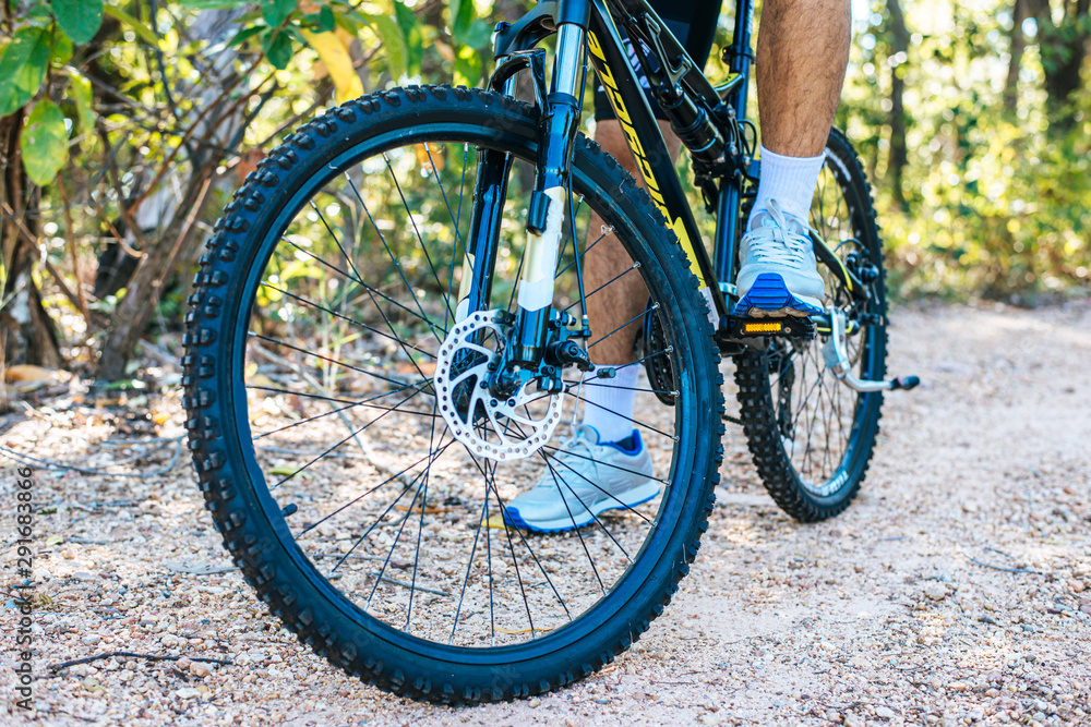 A low perspective of mountain cyclists on a rocky path at sunset focusing on car wheels. A low perspective of mountain cyclists on a rocky path at sunset focusing on car wheels.