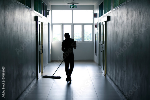Janitor woman mopping floor in hallway office building or walkway after school and classroom silhouette work job background. photo