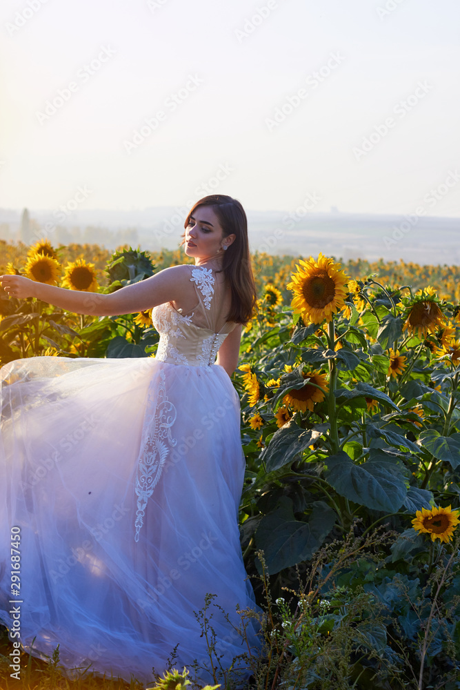 Beautiful young girl in a white dress enjoying nature on a field of ...