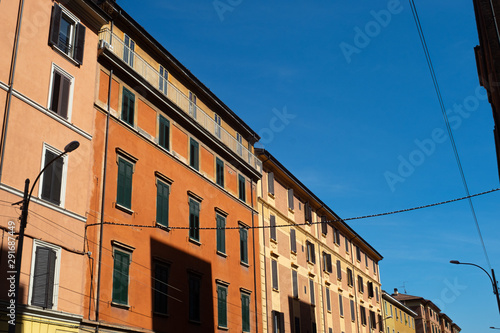 Orange, pink and yellow buildings in Bologna, Italy with blue sky in the background.