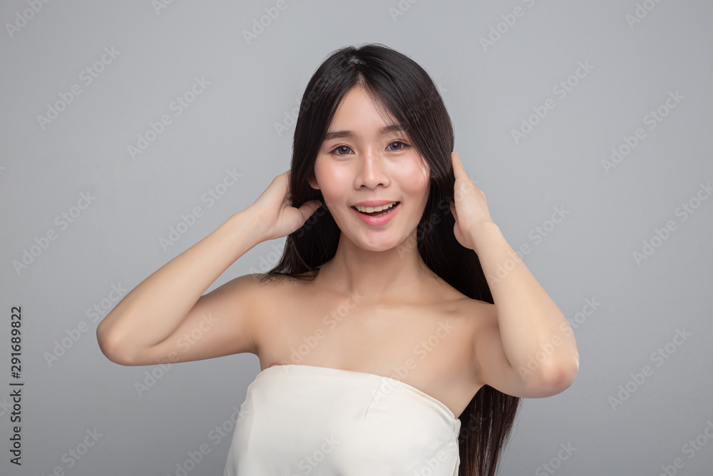 The woman wore a white strapless dress and stood touching her hair. The woman wore a white strapless dress and stood touching her hair.