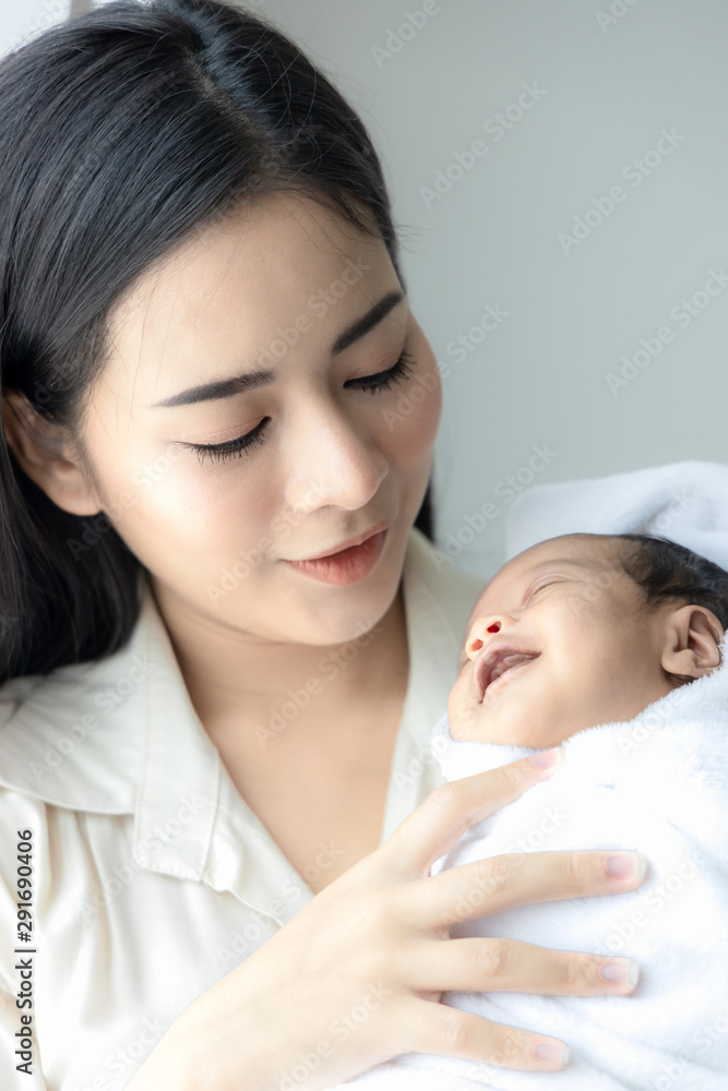 Portrait of young Asian mother happily hugs her lovely newborn baby. Wife and mother's day concept. Portrait of young Asian mother happily hugs her lovely newborn baby. Wife and mother's day concept.