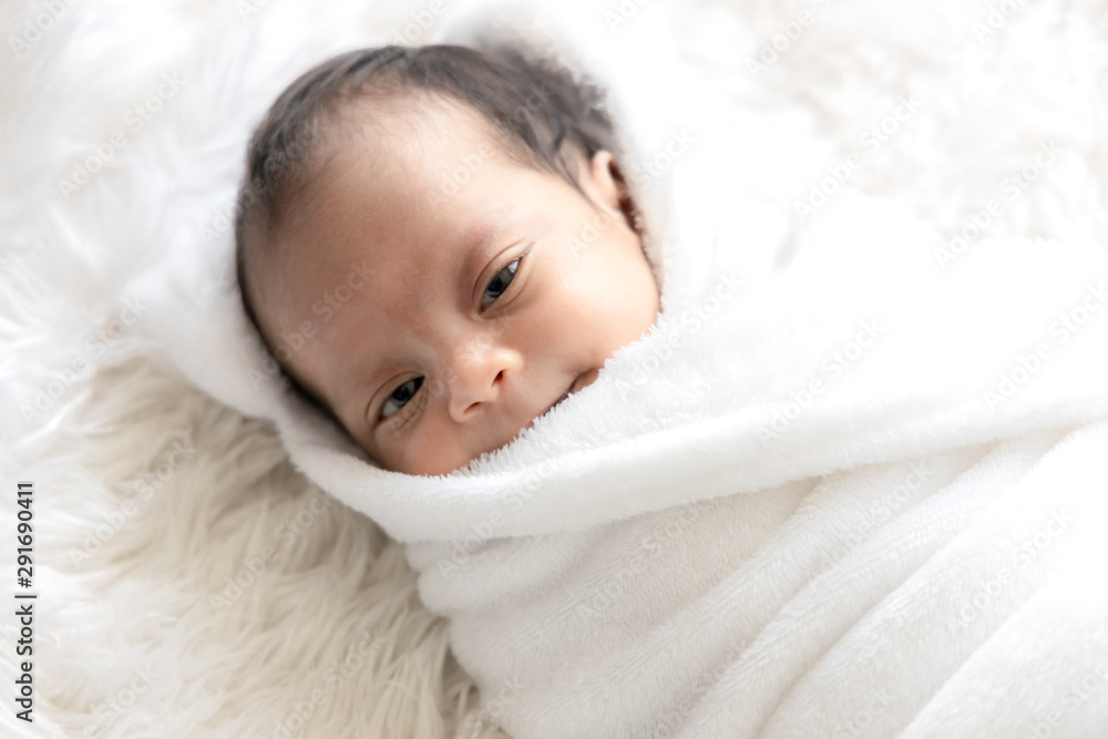 Portrait of cute newborn baby looking eye contact and smiling on white bed. Portrait of cute newborn baby looking eye contact and smiling on white bed.