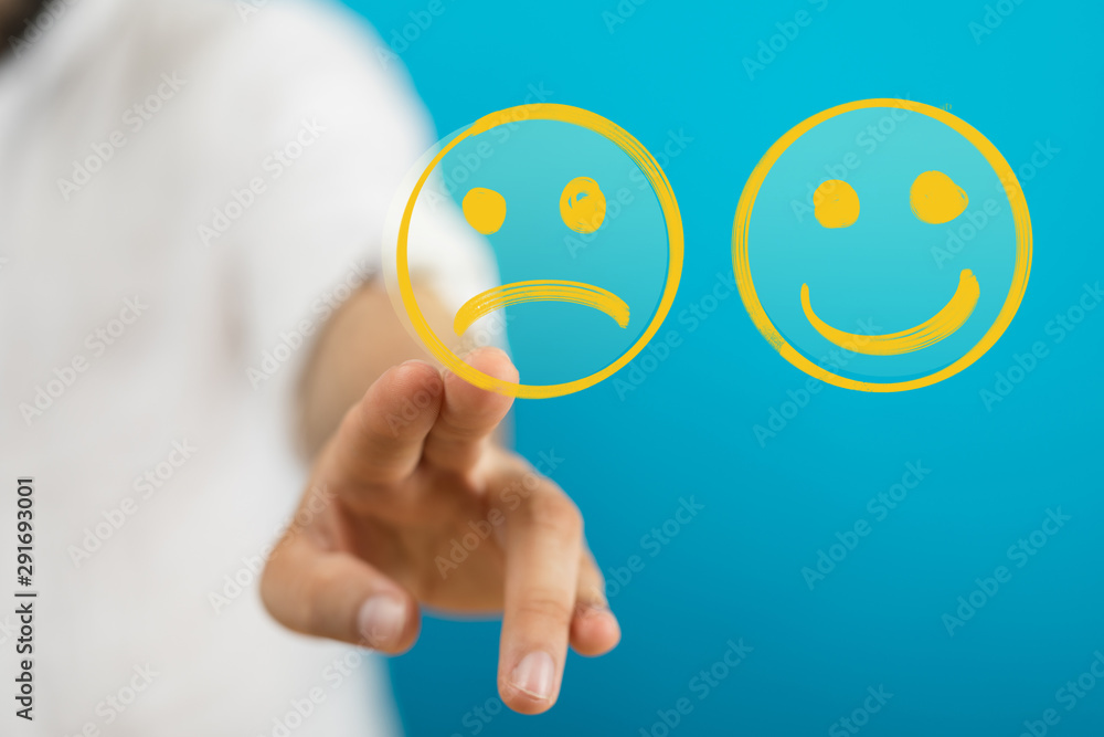 Hand is selecting a happy mood smiley. In front of an empty room Hand is selecting a happy mood smiley. In front of an empty room
