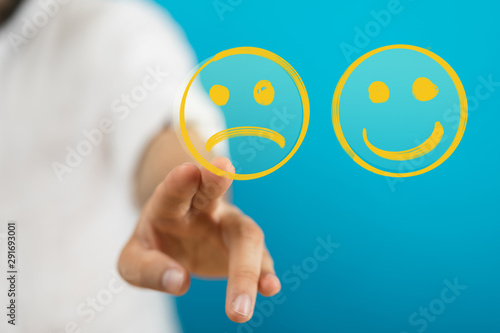 Hand is selecting a happy mood smiley. In front of an empty room
