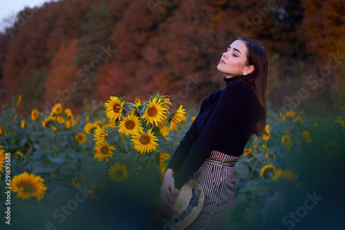 Beautiful lovely girl with a straw hat enjoying nature on a field of sunflowers. Sunset. Autumn time