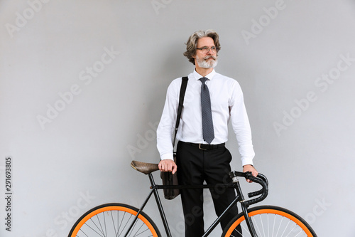 Photo of handsome mature businessman standing with bicycle