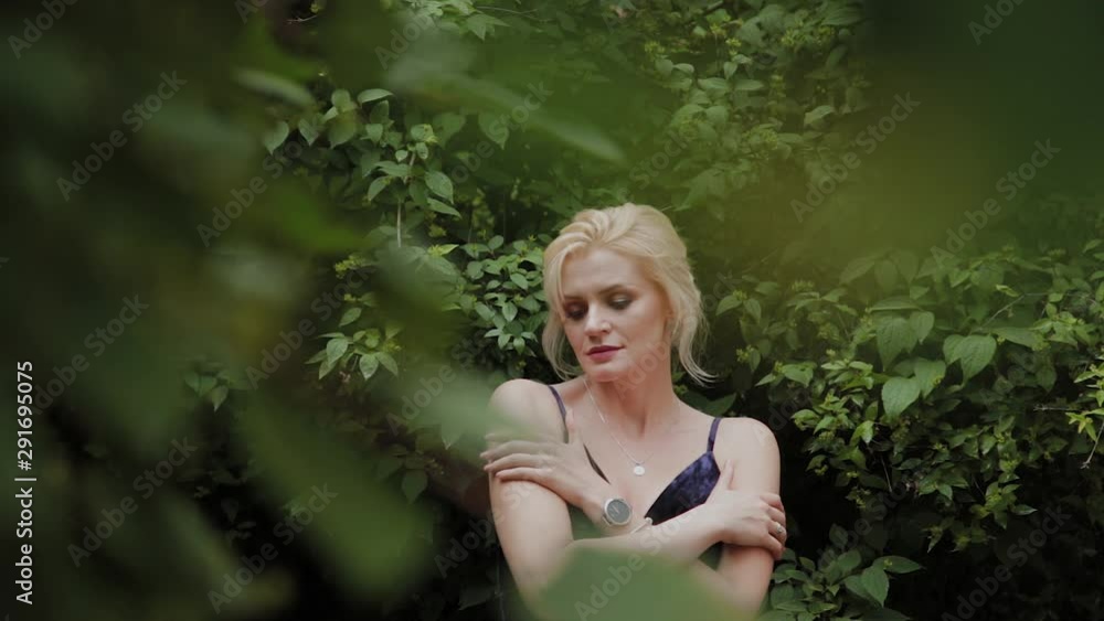 Beautiful woman photo model stands in green bushes in summer. Beautiful woman photo model stands in green bushes in summer.