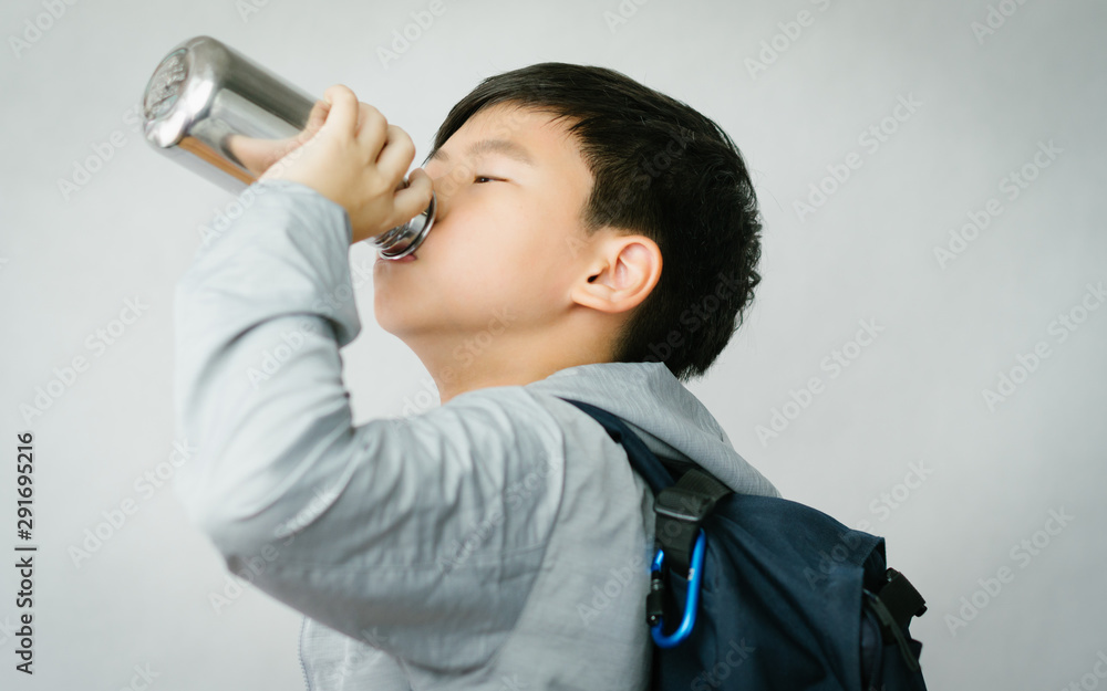 Fototapeta premium Eco-friendly lifestyle concept. Smart looking Asian preteen boy drinking water from reusable stainless steel water bottle. Sustainable lifestyle.