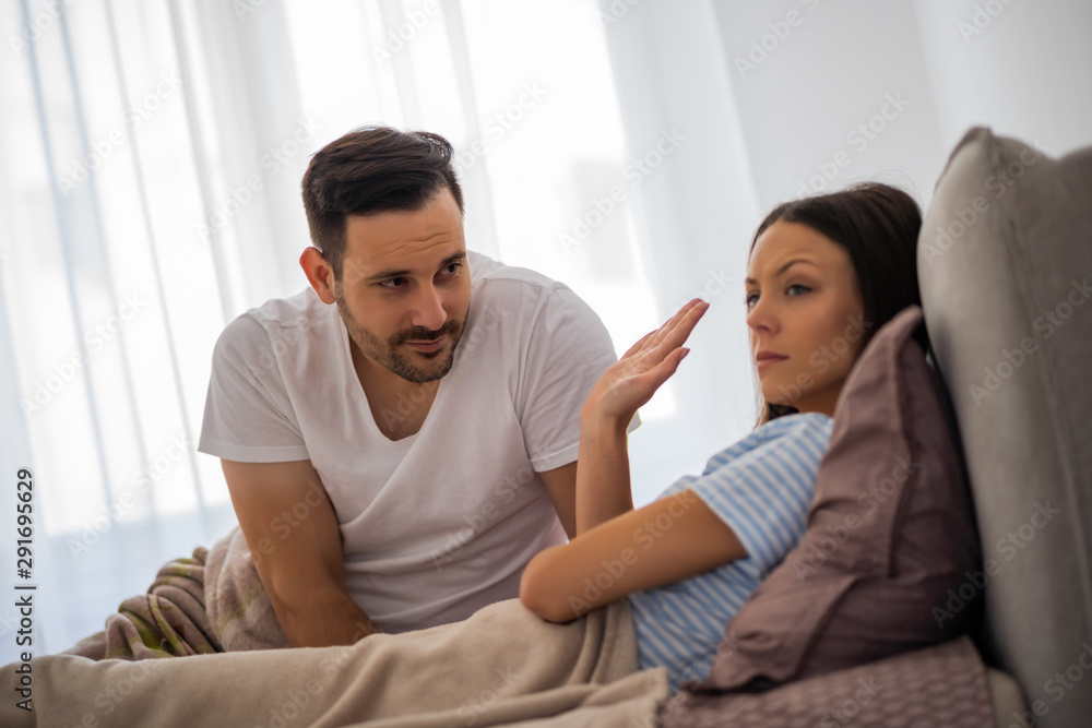 Young couple is arguing in bed. Woman is offended and angry. Young couple is arguing in bed. Woman is offended and angry.