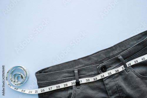 Εκτύπωση καμβά White measure tape with dark gray jeans on light pastel blue table