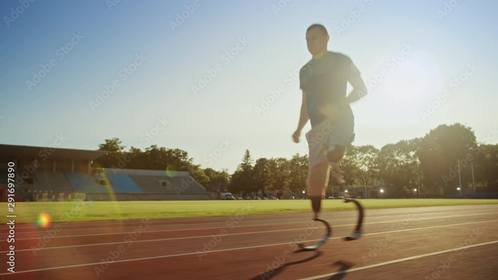 Athletic Disabled Fit Man with Prosthetic Running Blades is Training on a Outdoors Stadium on a Sunny Afternoon. Amputee Runner Jogging on a Stadium Track. Motivational Sports Footage. Tracking Shot.