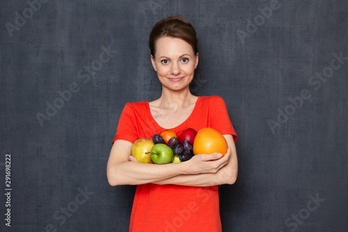 Portrait of happy young woman holding ripe fresh fruits in hands