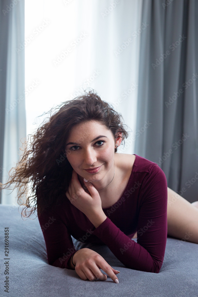 Young woman in a red bodysuit relaxing in bed. Young woman in a red bodysuit relaxing in bed.