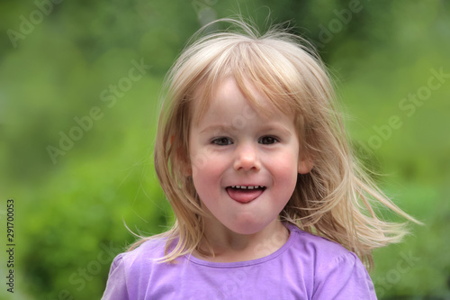 Portrait kleines blondes glückliches Mädchen steckt Zunge raus