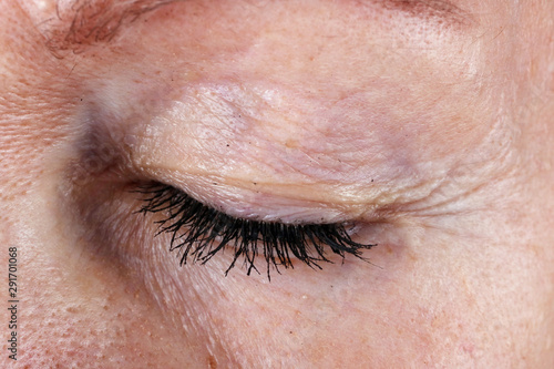 Closed  eye and eyelashes with lumps of black ink mascara from an old seniior elderly  woman photo