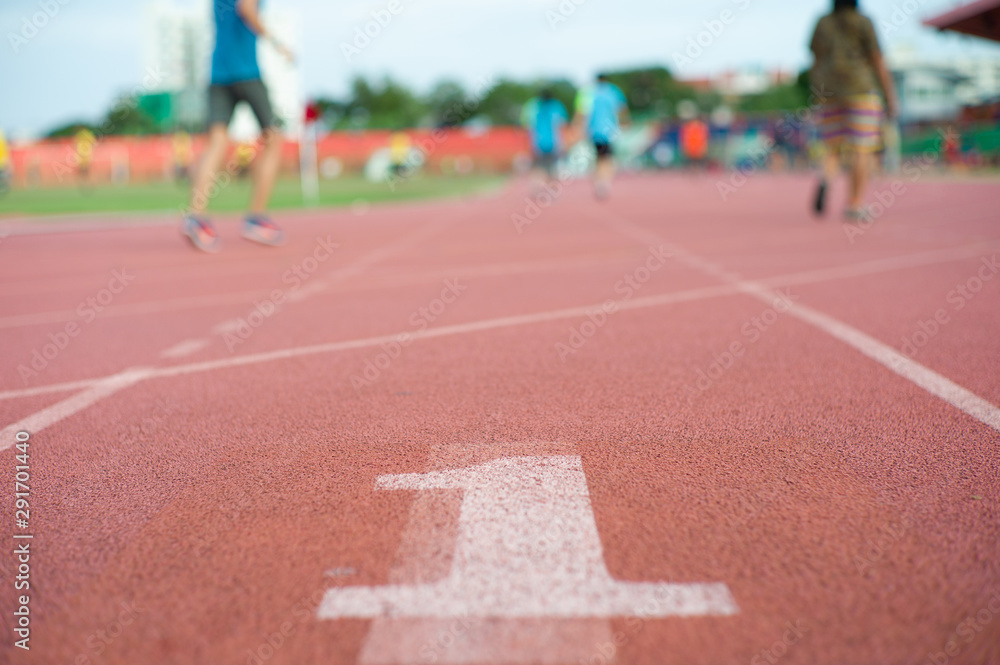 Abstract texture and background of empty running track with number one on the floor and defocused people  exercising in background