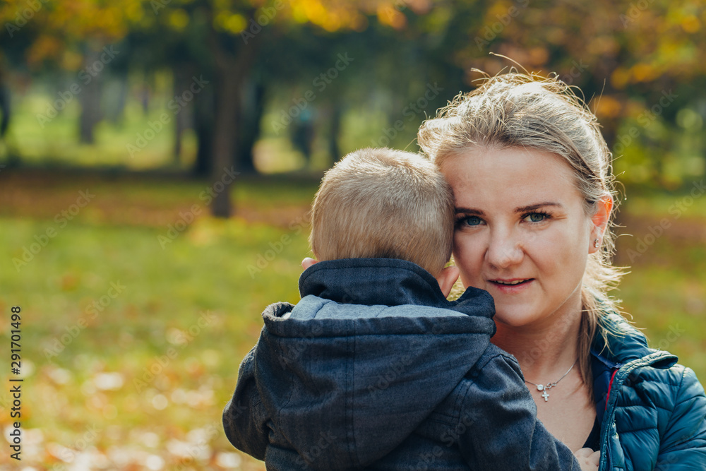 portrait of a beautiful young mother with her son walks in the autumn park. portrait of a beautiful young mother with her son walks in the autumn park.