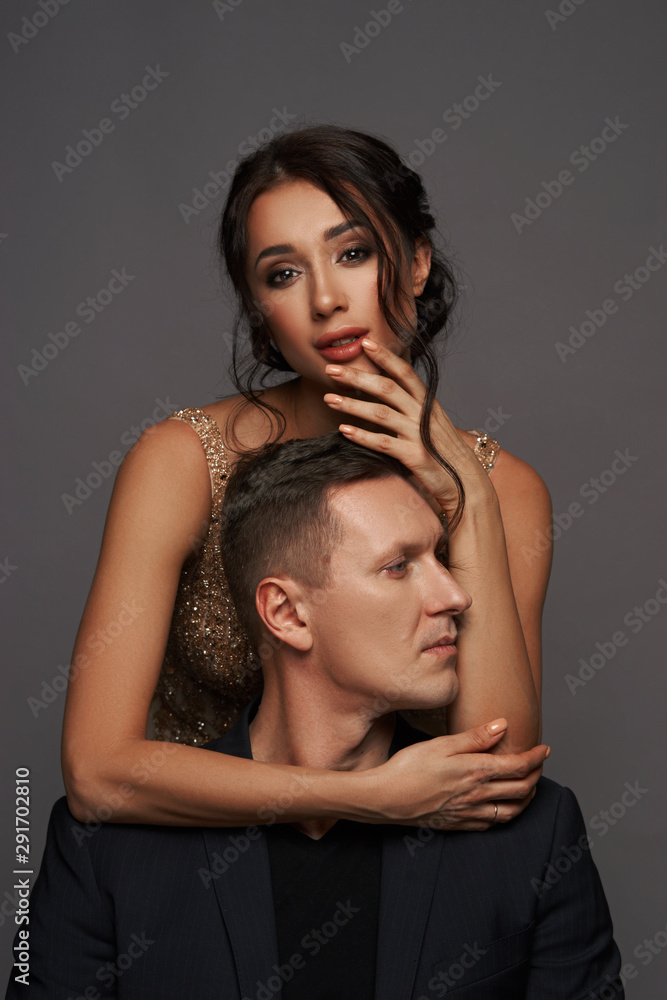 Close up portrait of oyung beautiful attractive adult coupe. Woman hugging man from back and looking in camera Close up portrait of oyung beautiful attractive adult coupe. Woman hugging man from back and looking in camera
