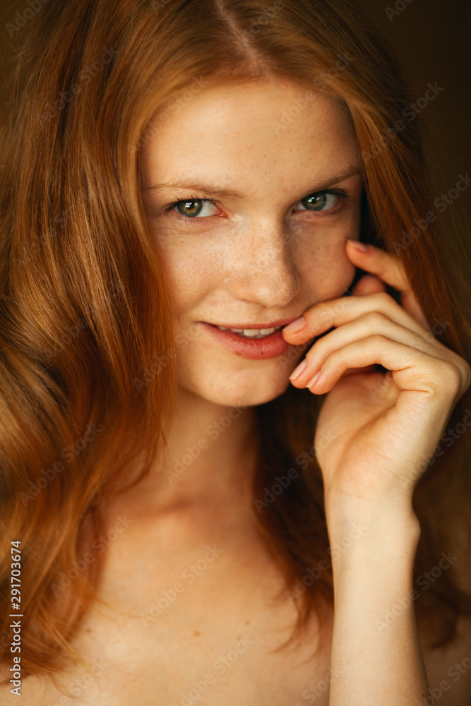 Emotive portrait of a fashionable model with red (ginger) wavy hair and natural make-up. Great white shiny smile. Perfect skin with freckles. Retro style. Close up. Studio shot Emotive portrait of a fashionable model with red (ginger) wavy hair and natural make-up. Great white shiny smile. Perfect skin with freckles. Retro style. Close up. Studio shot