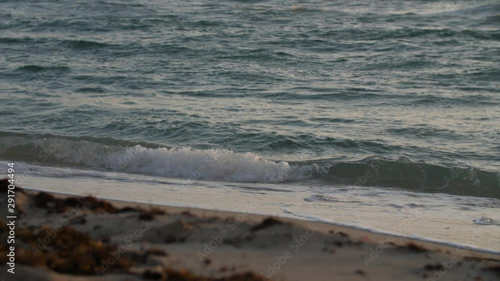 Handheld slow motion shot of the sea waves hitting the sandy beach Handheld slow motion shot of the sea waves hitting the sandy beach