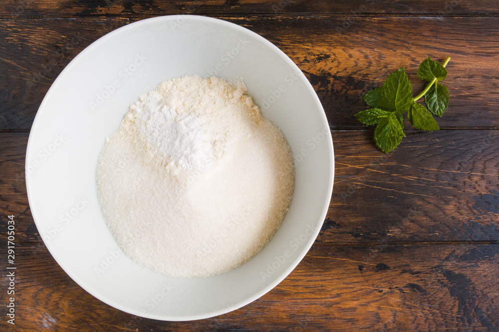 Dough making, flour, sugar and baking powder in white bowl. Wooden rustic table, top view Dough making, flour, sugar and baking powder in white bowl. Wooden rustic table, top view