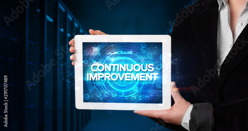 Wallpaper Mural Young business person working on tablet and shows the inscription: CONTINUOUS IMPROVEMENT, business concept Torontodigital.ca