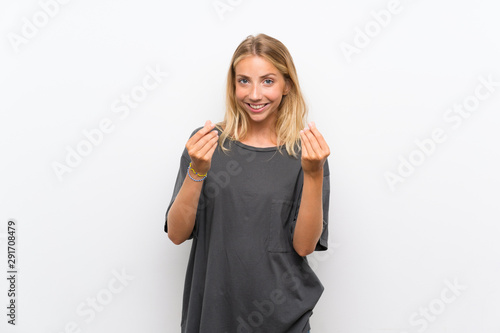 Blonde young woman over isolated white background making money gesture