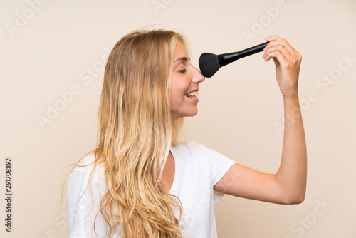 Happy Young blonde woman with makeup brush.
