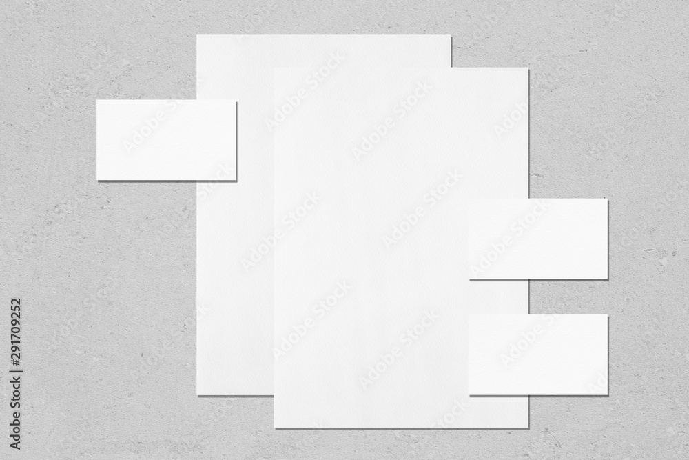 Two empty white vertical a4 sized posters and three horizontal rectangle business card mockups with soft shadows on neutral light grey concrete background. Flat lay, top view Two empty white vertical a4 sized posters and three horizontal rectangle business card mockups with soft shadows on neutral light grey concrete background. Flat lay, top view