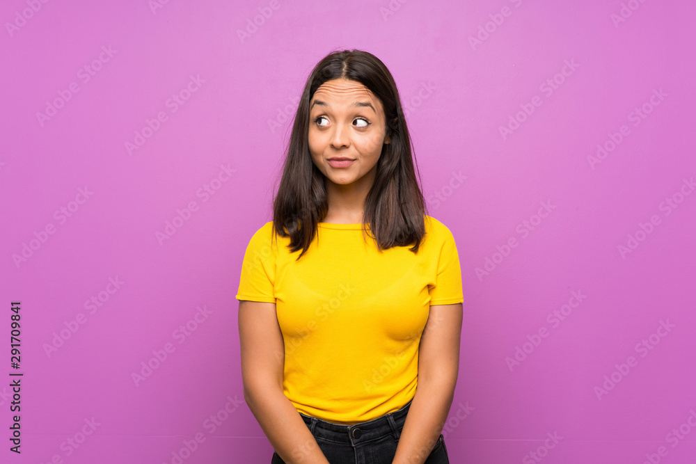 Young brunette girl over isolated background making doubts gesture looking side Young brunette girl over isolated background making doubts gesture looking side
