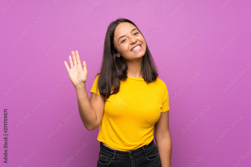 Young brunette girl over isolated background saluting with hand with happy expression Young brunette girl over isolated background saluting with hand with happy expression