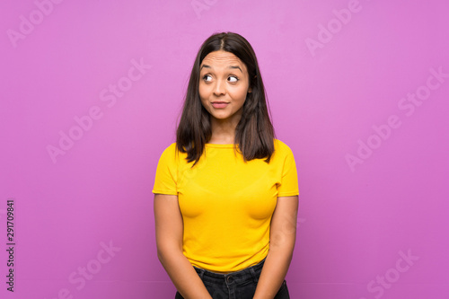 Young brunette girl over isolated background making doubts gesture looking side
