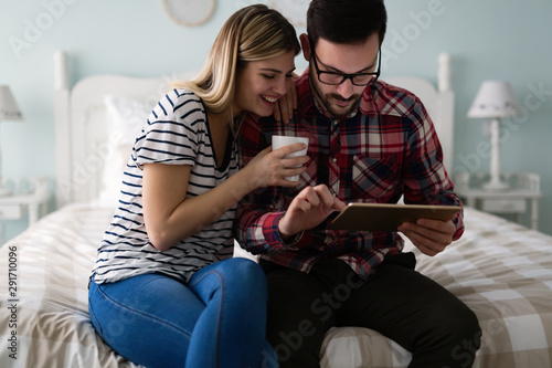 Young attractive couple using tablet in bedroom