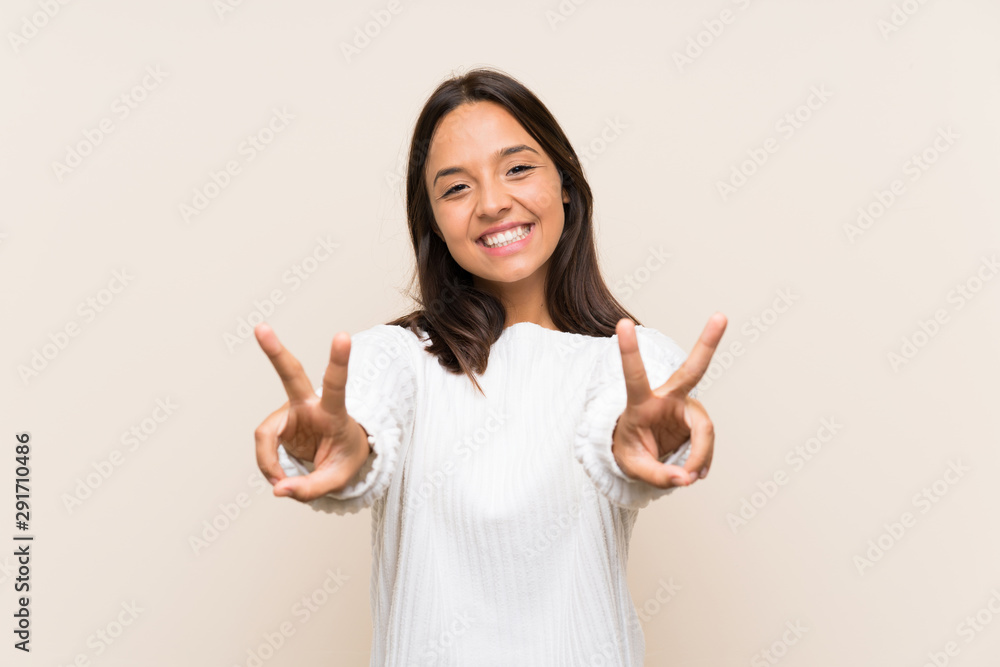 Young brunette woman with white sweater over isolated background smiling and showing victory sign Young brunette woman with white sweater over isolated background smiling and showing victory sign